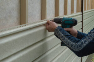 Worker installing residential vinyl siding on a home exterior