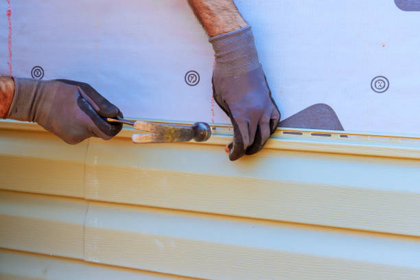 Worker installing vinyl siding using a hammer and tool