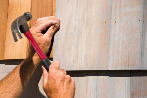 Installing cedar siding on a residential home with a hammer