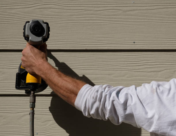 Close-up of worker installing engineered wood siding using power drill