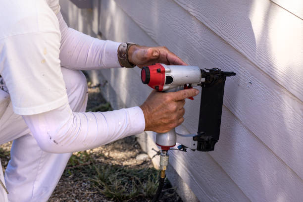 Worker using a pneumatic tool to install fiber cement siding